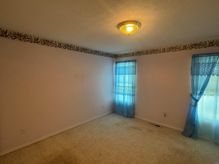 Unfurnished room featuring a textured ceiling and carpet flooring
