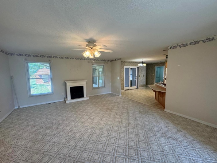 Unfurnished living room with ceiling fan and a textured ceiling