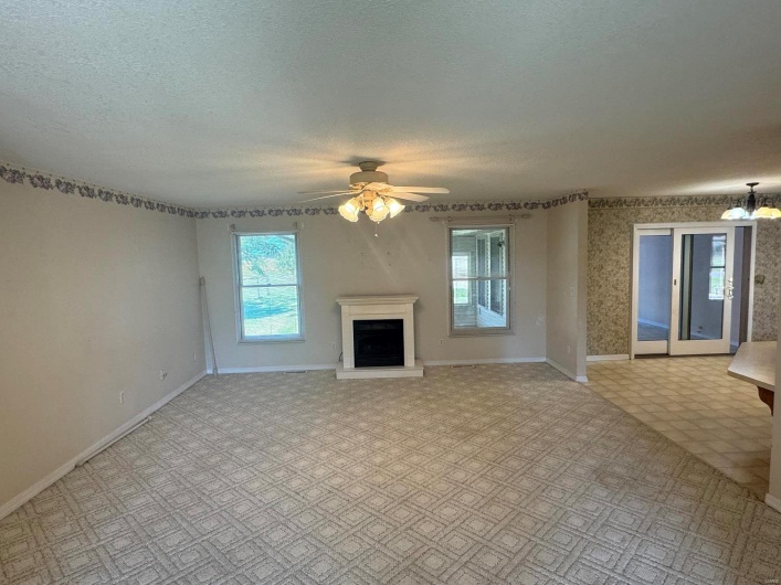 Unfurnished living room featuring a textured ceiling and ceiling fan with notable chandelier