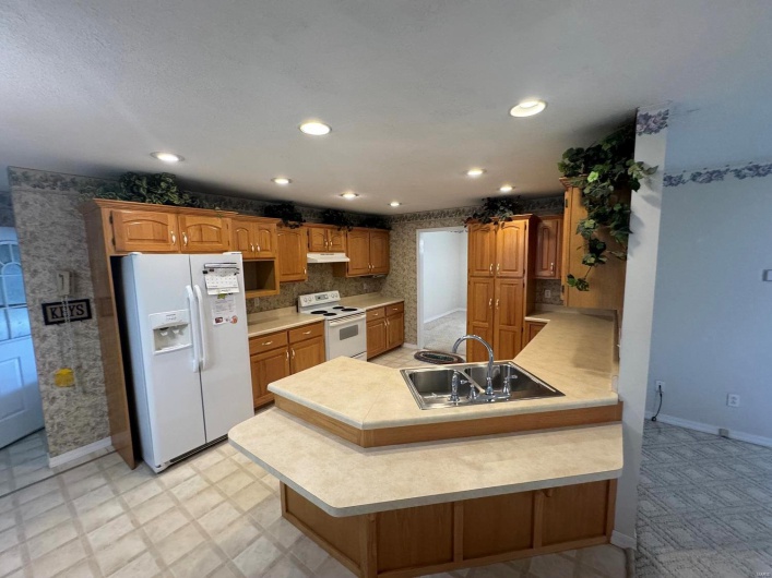 Kitchen featuring kitchen peninsula, sink, and white appliances