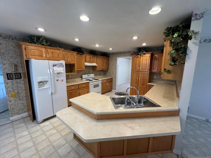 Kitchen featuring white appliances, a kitchen bar, sink, and kitchen peninsula
