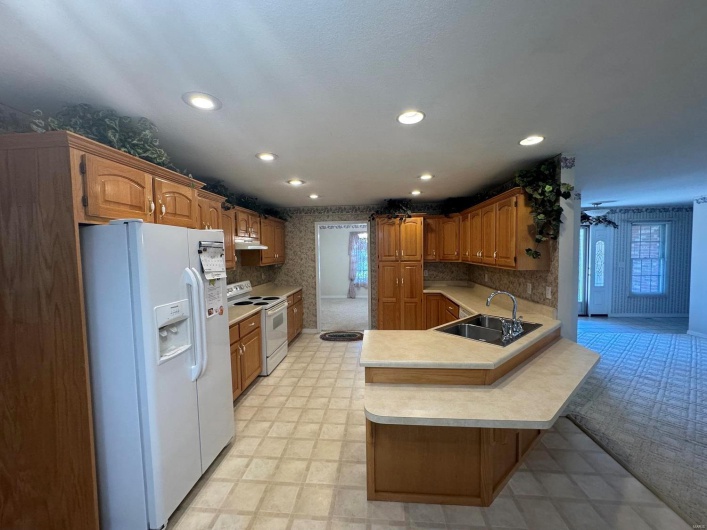 Kitchen featuring a kitchen bar, kitchen peninsula, sink, and white appliances
