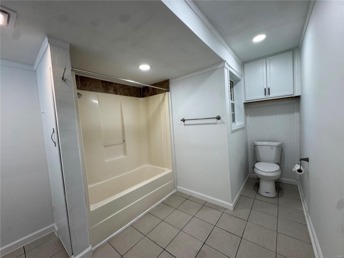 Full bathroom featuring tile patterned floors, toilet, baseboards, and shower / bathing tub combination