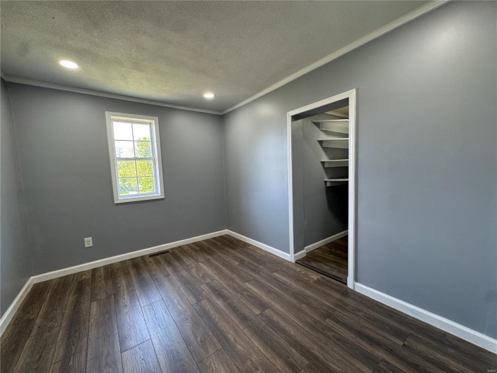 Unfurnished room featuring baseboards, dark wood finished floors, and a textured ceiling