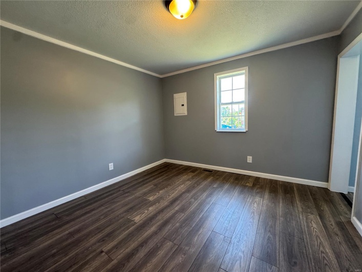 Unfurnished room featuring baseboards, dark wood finished floors, crown molding, and a textured ceiling