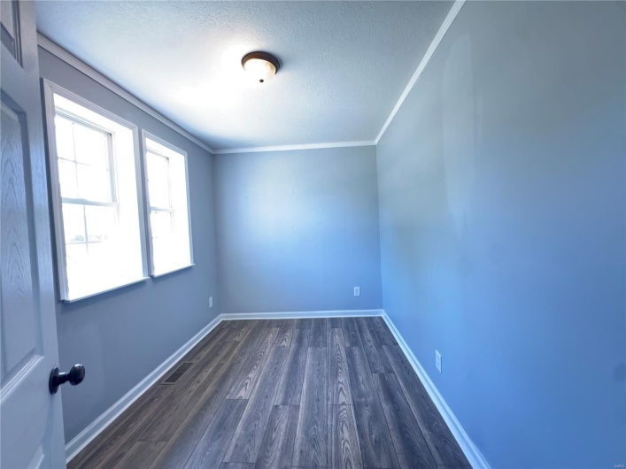 Unfurnished room with baseboards, dark wood-style flooring, and a textured ceiling