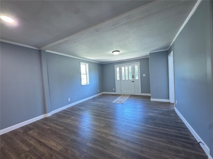 Entrance foyer featuring dark wood-style flooring, crown molding, and baseboards
