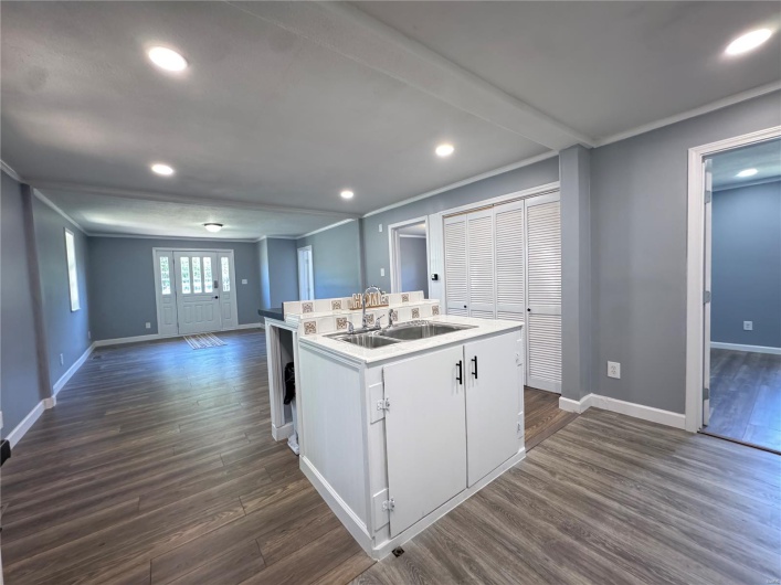 Kitchen featuring recessed lighting, baseboards, dark wood finished floors, a sink, and a center island with sink