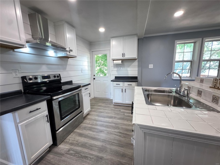 Kitchen with stainless steel electric range oven, wall chimney range hood, recessed lighting, and a sink