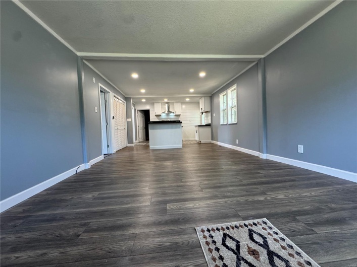 Unfurnished living room featuring recessed lighting, baseboards, and dark wood-style floors