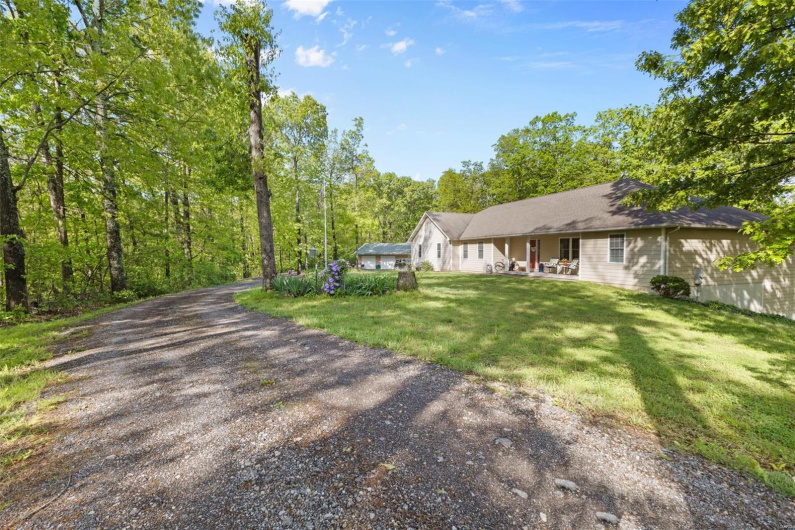 View of front of home featuring gravel driveway, a front lawn, and covered porch
