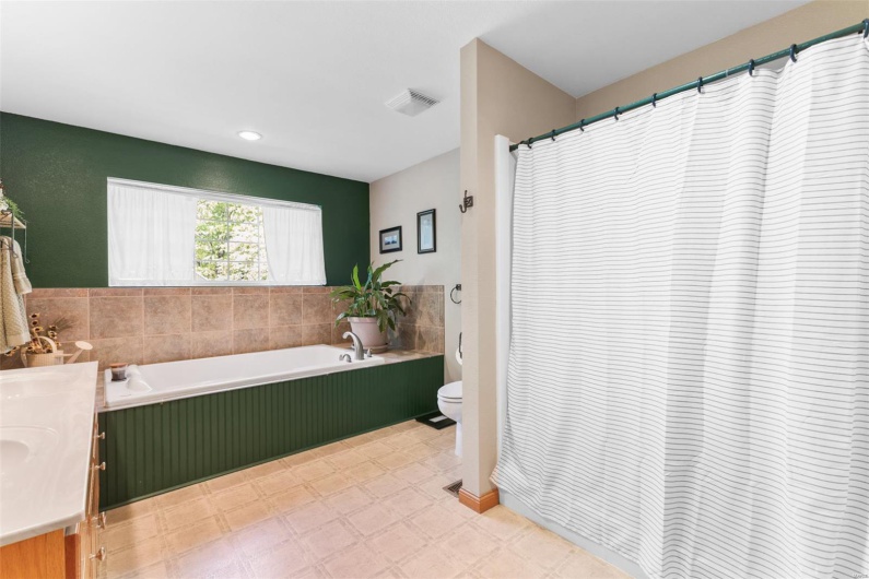 Full bath featuring toilet, vanity, visible vents, tile patterned floors, and a garden tub