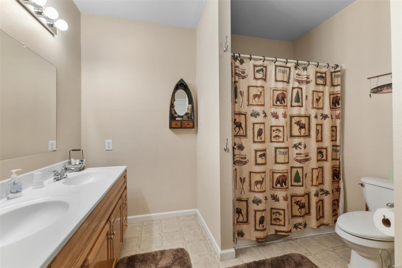 Bathroom with toilet, double vanity, a sink, and curtained shower