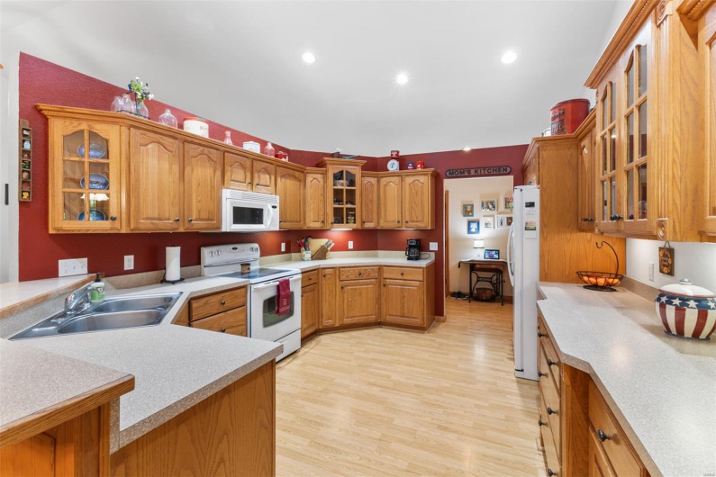 Kitchen with light countertops, glass insert cabinets, a sink, and white appliances