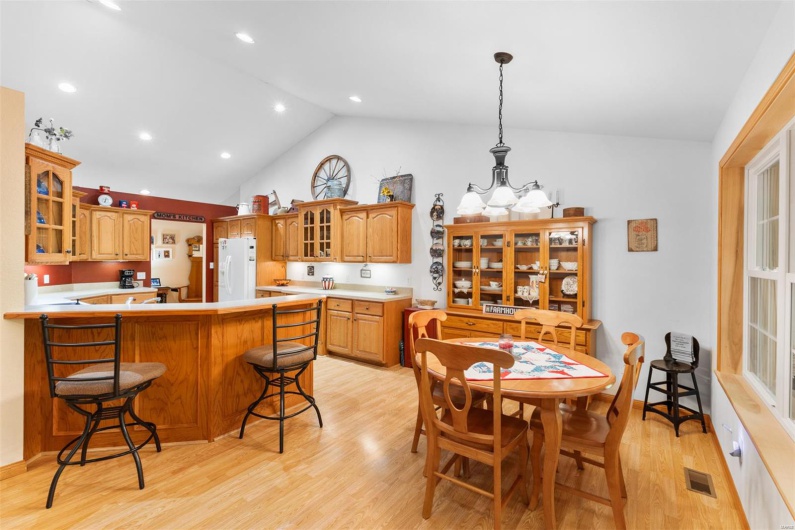 Dining space featuring light wood-style flooring, high vaulted ceiling, visible vents, and recessed lighting