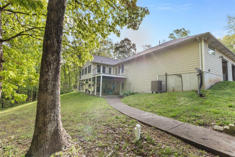 Rear view of property featuring central AC unit, a yard, and a balcony