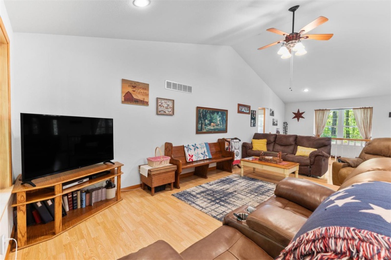 Living room with wood finished floors, visible vents, recessed lighting, vaulted ceiling, and a ceiling fan