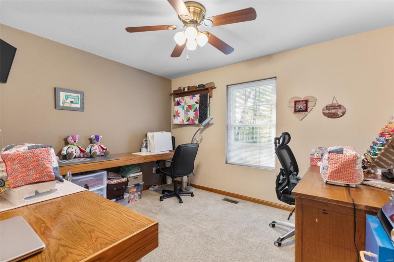 Carpeted home office featuring baseboards and ceiling fan