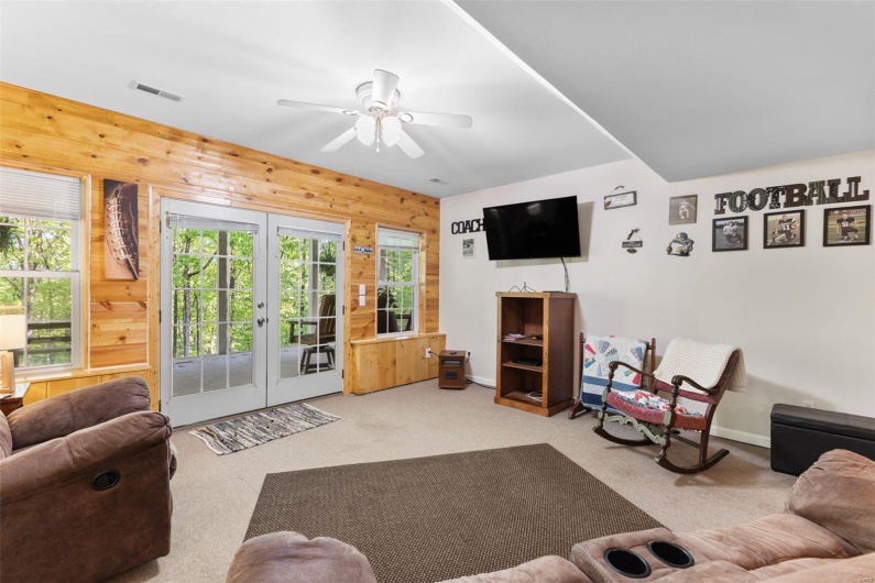 Living area featuring plenty of natural light, wooden walls, a ceiling fan, and carpet floors