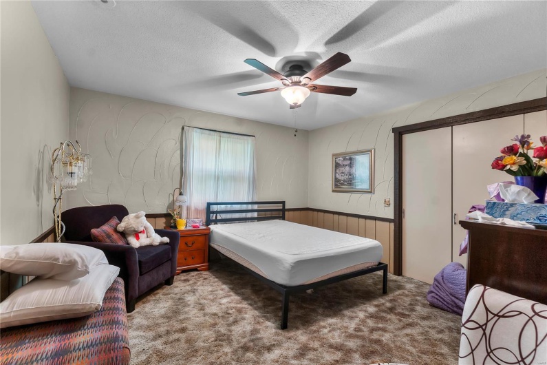 Carpeted bedroom with wainscoting, ceiling fan, a textured ceiling, and a closet