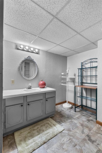 Basement Bathroom with a paneled ceiling, baseboards, vanity, and a textured wall