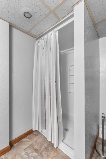 Basement Full bathroom with a shower with shower curtain and baseboards