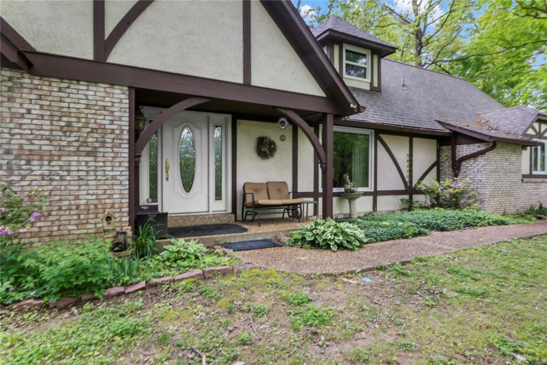 Property entrance featuring stucco siding, roof with shingles, and brick siding