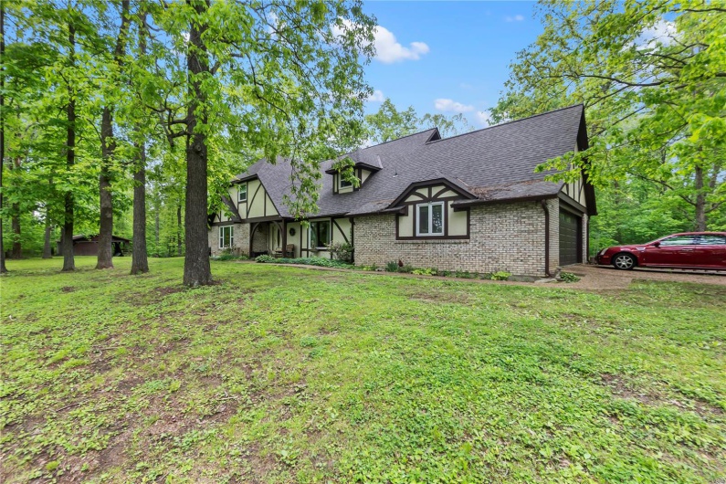 View of front of house featuring roof with shingles, brick siding, and a front yard