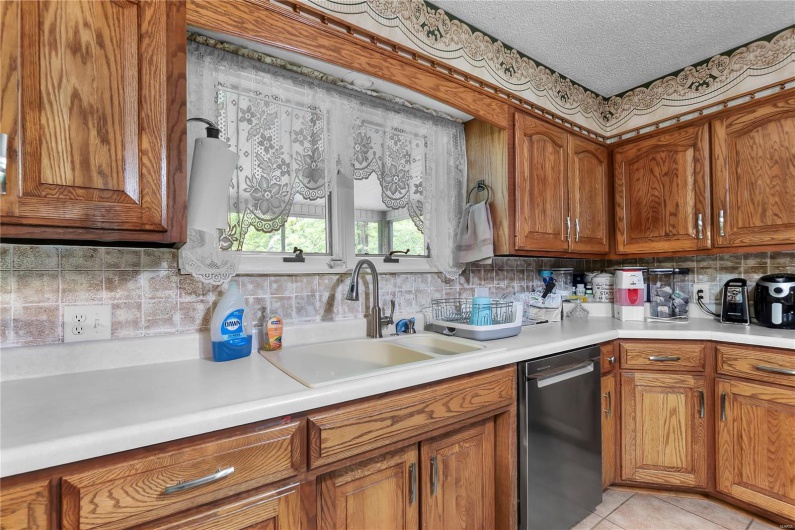Kitchen featuring a sink, brown cabinetry, decorative backsplash, and dishwasher