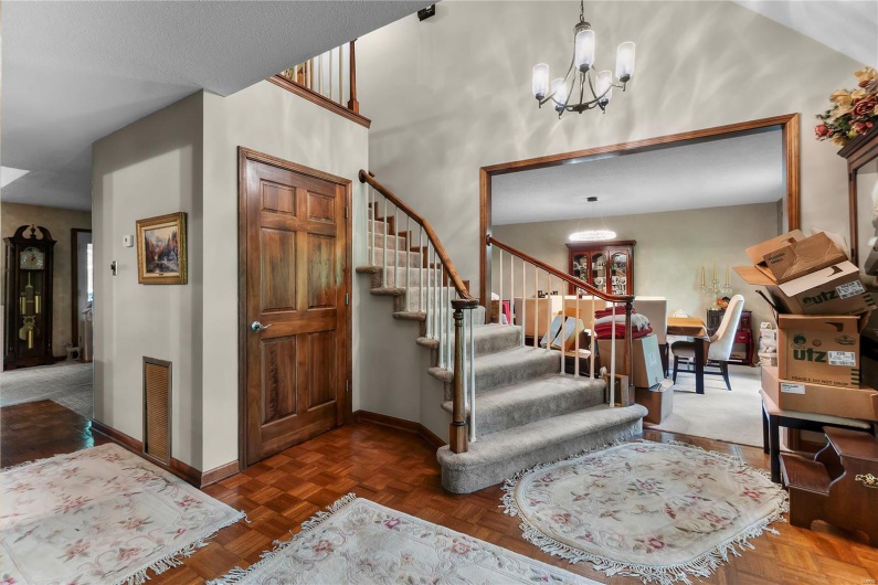 Foyer entrance with an inviting chandelier, stairs, and baseboards
