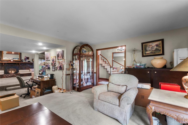 Carpeted living area with stairway and a stone fireplace