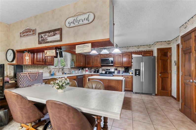 Kitchen featuring a sink, tasteful backsplash, a textured ceiling, light countertops, and appliances with stainless steel finishes