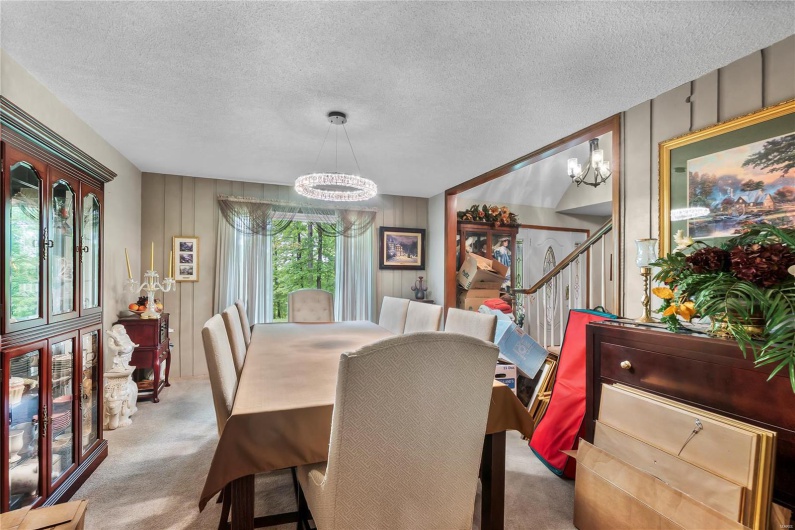 Dining area featuring carpet, a textured ceiling, stairway, and a notable chandelier