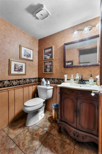 Half bathroom featuring toilet, tile patterned floors, vanity, and a textured ceiling