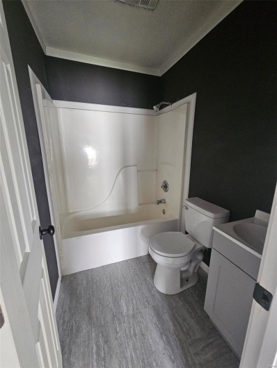 Bathroom featuring toilet, wood finished floors, shower / bathtub combination, vanity, and a textured ceiling