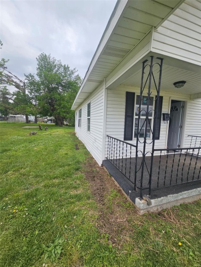 View of side of property with a yard and covered porch