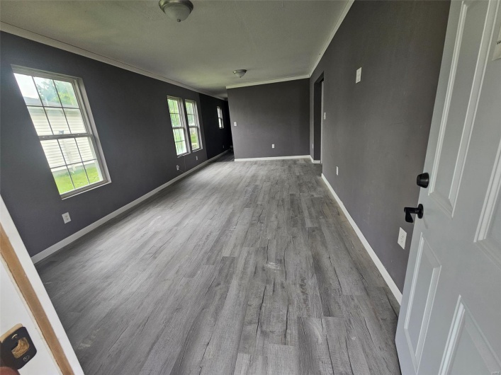 Empty room with wood finished floors, baseboards, and ornamental molding