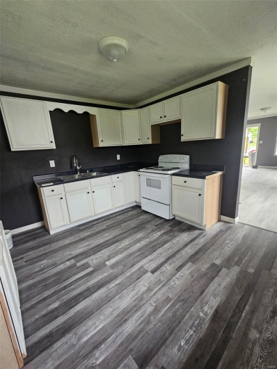 Kitchen with white range with electric stovetop, a sink, dark wood-type flooring, dark countertops, and a textured ceiling