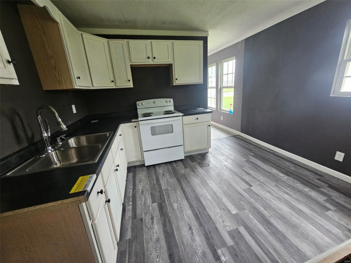 Kitchen with white range with electric cooktop, a sink, dark wood finished floors, dark countertops, and a textured ceiling