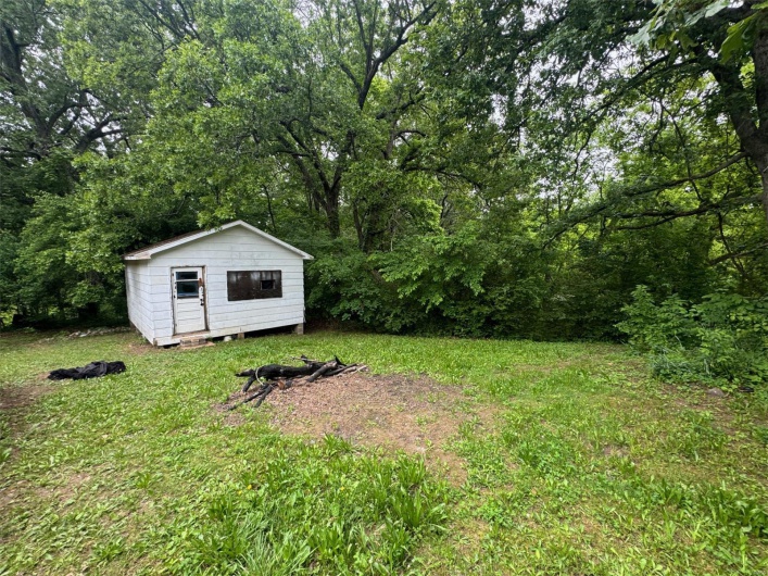 View of green lawn with a storage unit and an outdoor structure