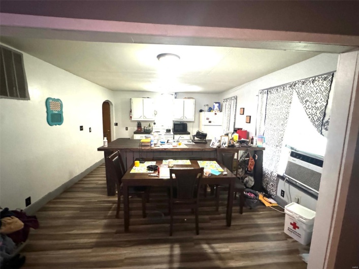 Dining space with arched walkways and dark wood finished floors