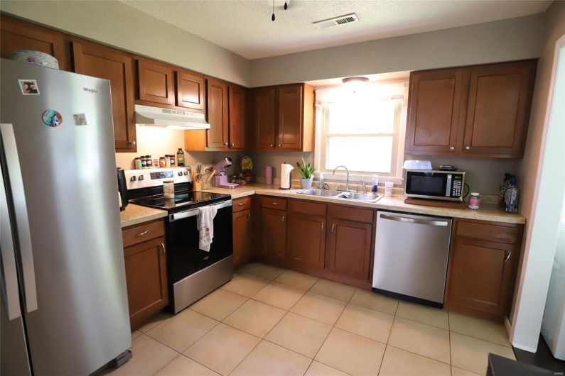 Kitchen featuring appliances with stainless steel finishes, a sink, under cabinet range hood, and light countertops