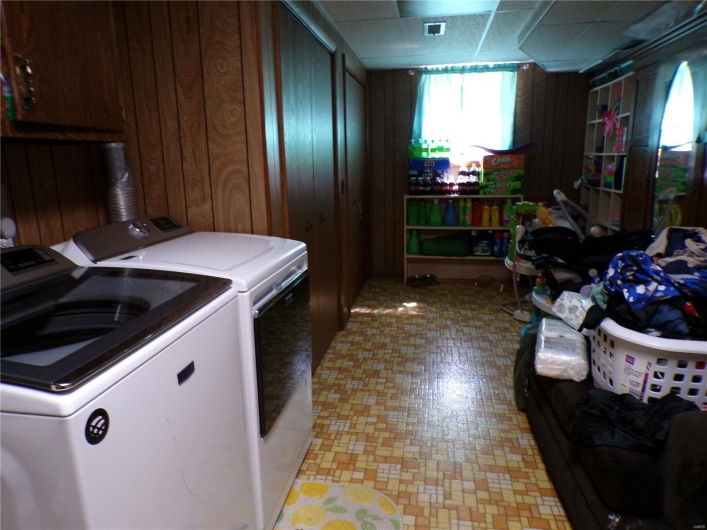 Clothes washing area featuring washer/dryer and ample storage area.