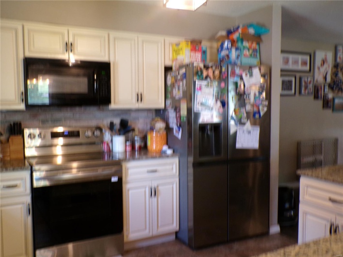 Kitchen with stainless steel and black appliances, and white cabinetry.