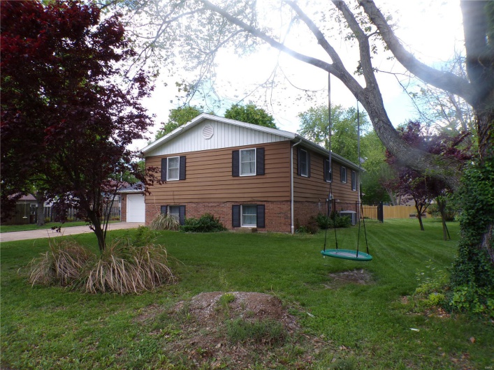 View of side of property with a lawn, driveway, a garage, and brick/vinyl siding