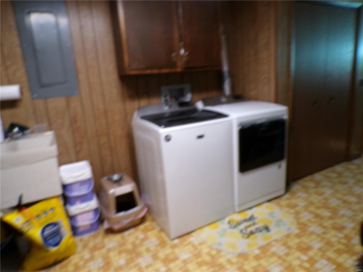 Clothes washing area featuring washing machine and clothes dryer, cabinet space, and electric panel.