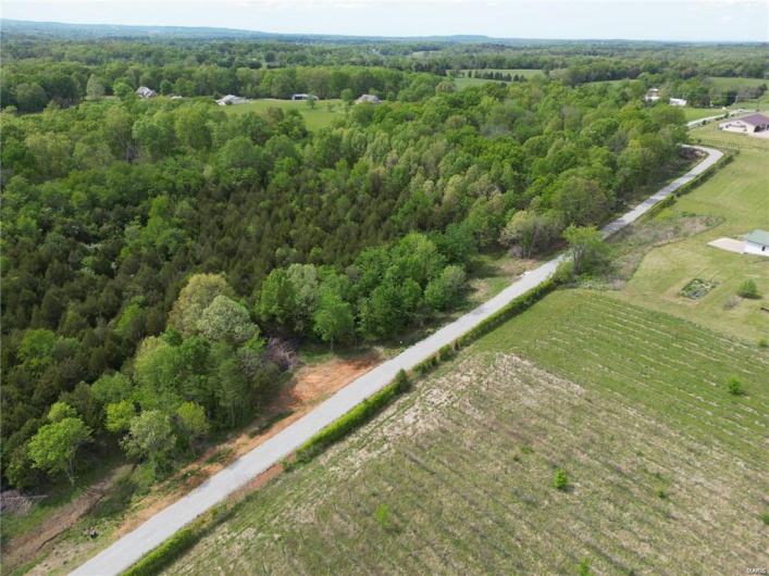 Aerial view of property and surrounding area featuring a forest and rural landscape