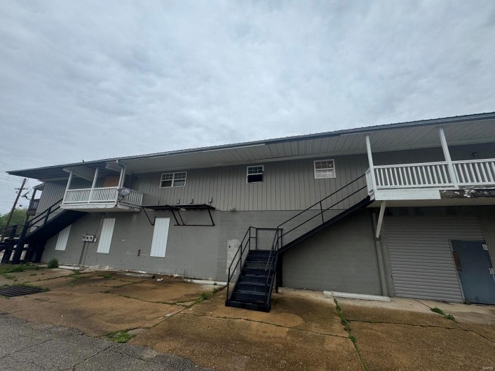Back of property with stairway and concrete block siding