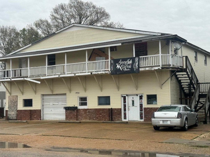 Townhome / multi-family property with an attached garage, brick siding, stairway, and concrete driveway