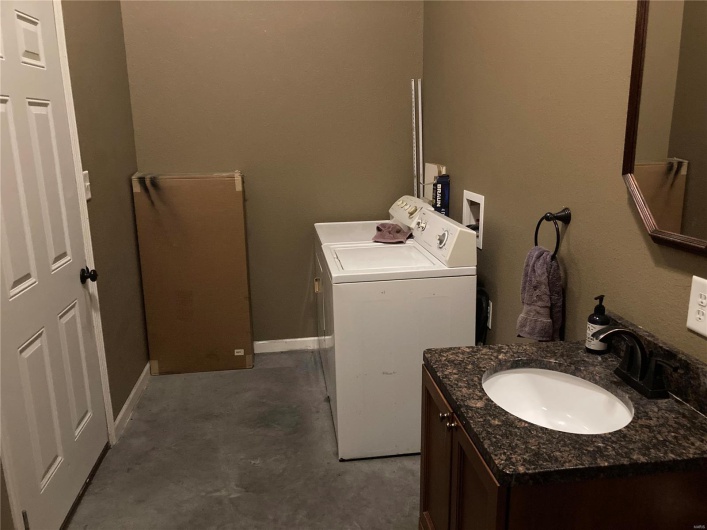Bathroom featuring washer and dryer, vanity, and concrete flooring